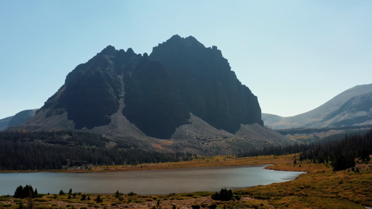 impresionante paisaje de drones aéreos naturaleza dolly en la toma de un gran prado con un pequeño arroyo con el hermoso lago del castillo rojo inferior y pico detrás en el bosque nacional de uinta alto en utah