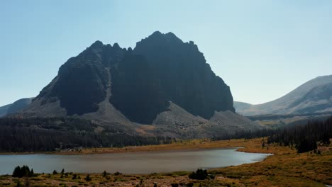 Stunning-aerial-drone-landscape-nature-dolly-in-shot-of-a-large-meadow-with-a-small-stream-with-the-beautiful-Lower-Red-Castle-Lake-and-peak-behind-up-in-the-High-Uinta-national-forest-in-Utah