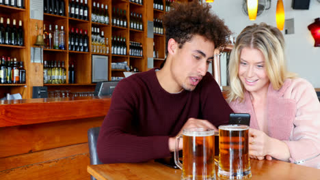 couple using mobile phone while having glass of beer 4k