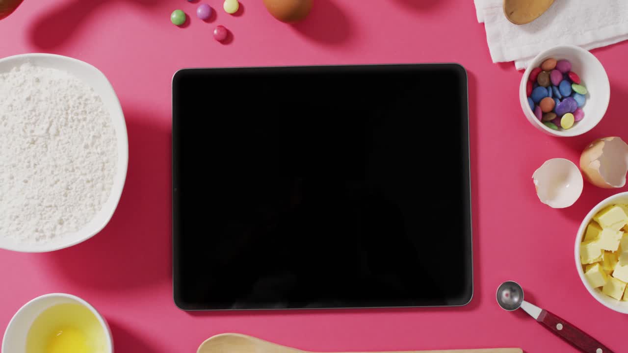 video de ingredientes y herramientas de horneado en la superficie rosa con tableta con espacio de copia