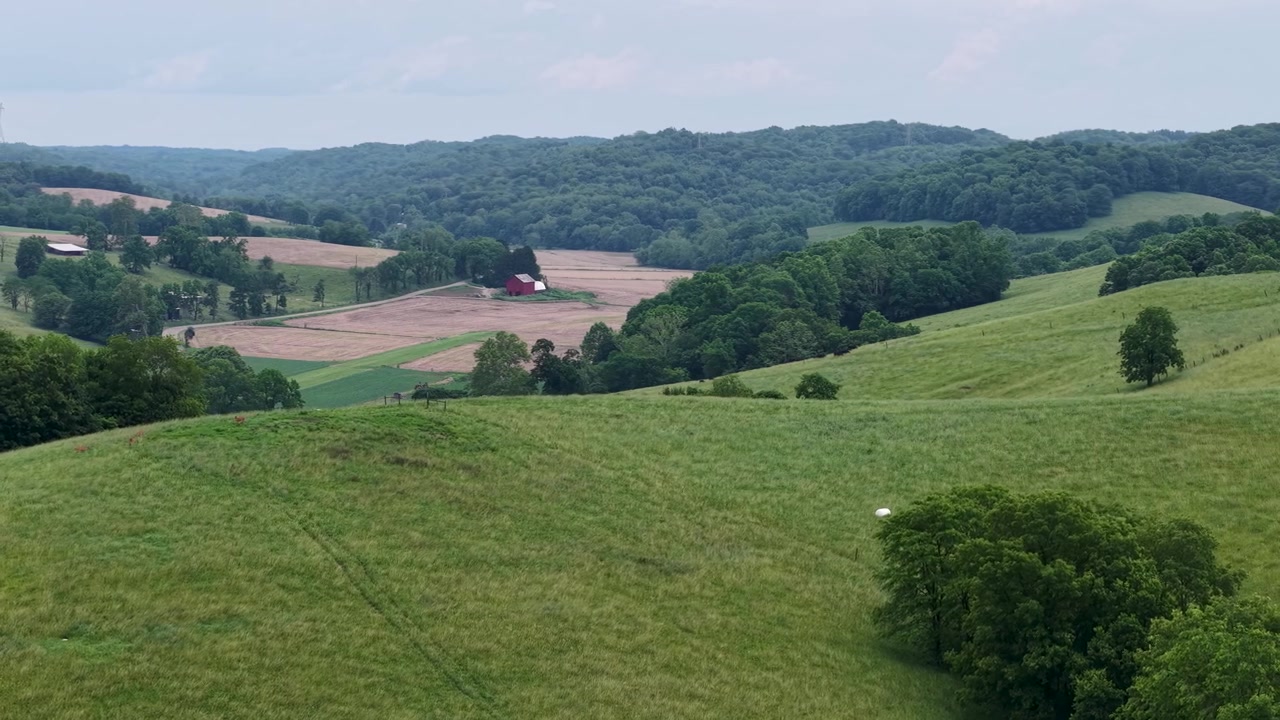 Broad green pasture slopes toward wooded valleys and distant ridges in the Ohio countryside