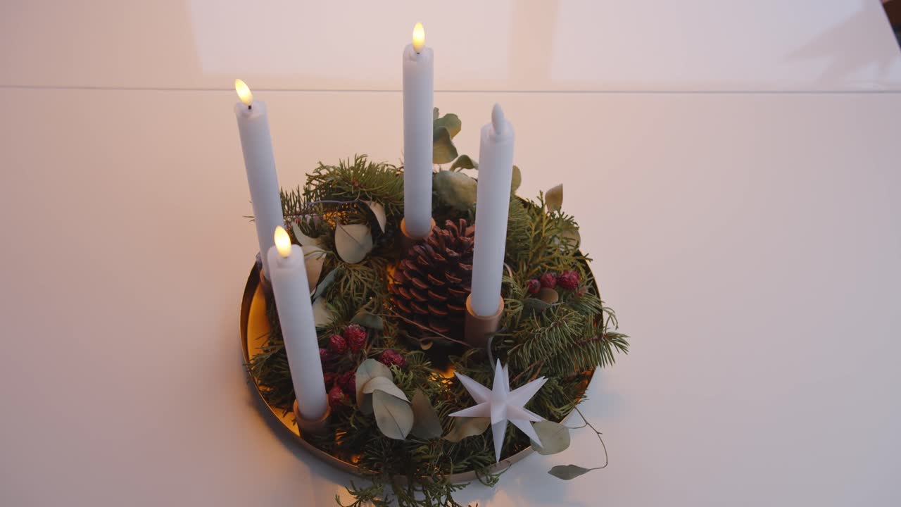 Hand lighting Advent wreath candles with festive pine and floral arrangement