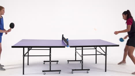 competing in table tennis, two people playing in studio setting