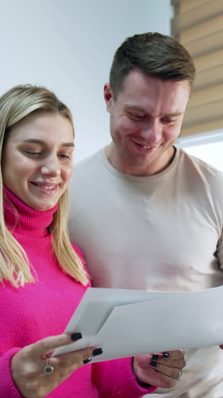 Caucasian couple looking through the images. Happy future parents see their future baby ultrasound scans. Vertical video