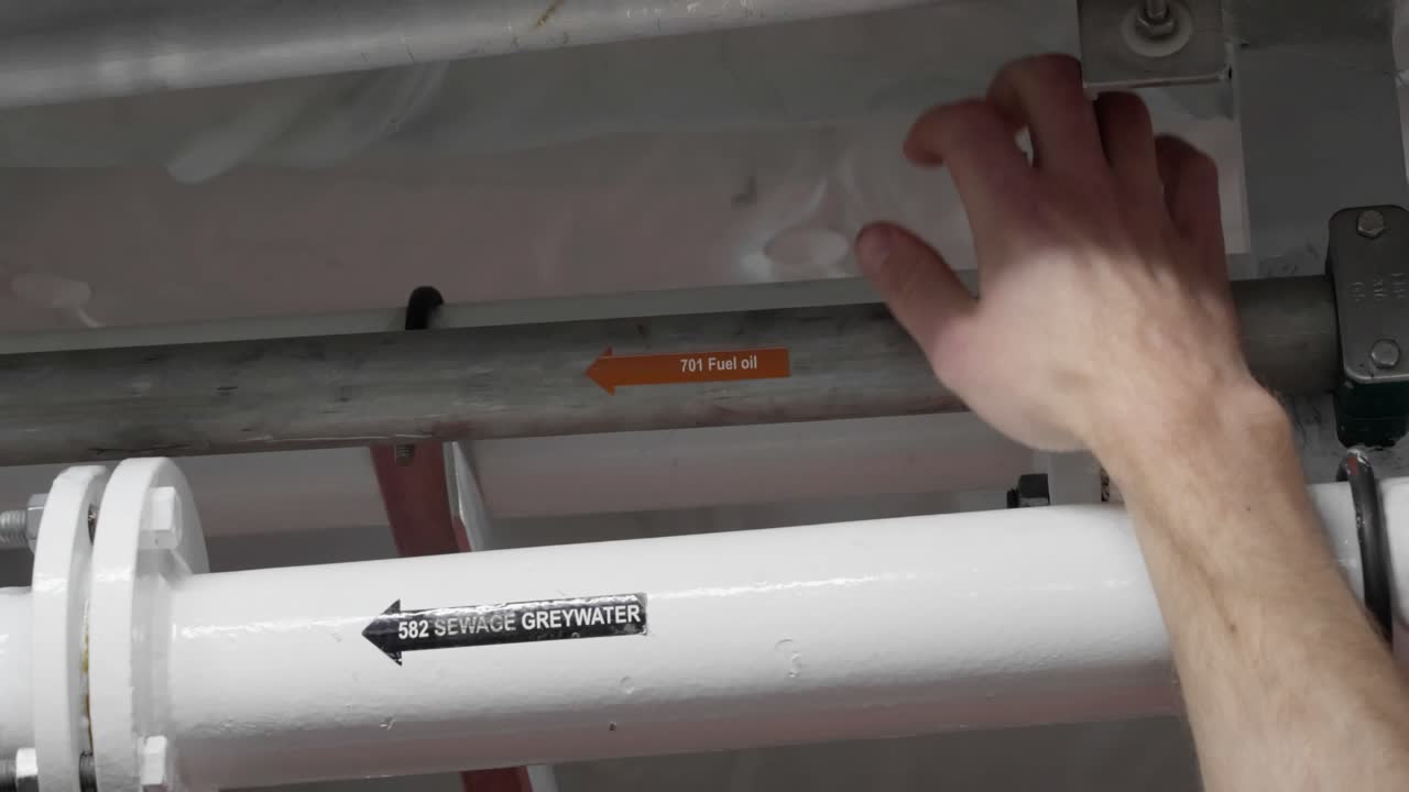 mano del capitán mostrando la tubería de combustible en el techo de la zona de la sala de máquinas de los barcos