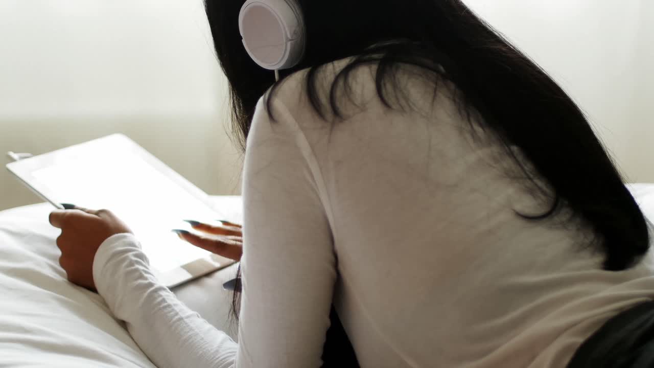 침실에서 디지털 태블릿을 사용하는 여성