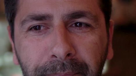 un hombre sonriente y de buena disposición con una capucha en la cabeza, mira a la habitación y come una comida tradicional