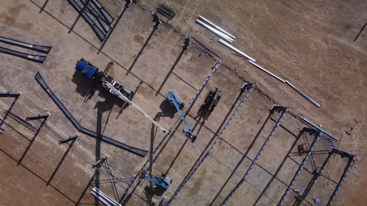 Metal frame construction site pull out machinery pan top down crane drone aerial sunny