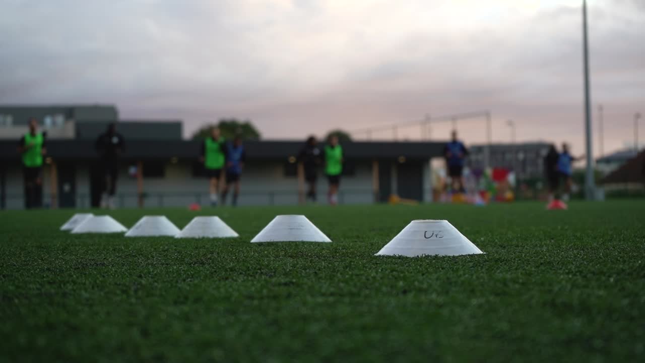 노란색 디스크가 잔디밭 축구 훈련을 하는 한 무리의 젊은이들을 지나쳐갑니다.