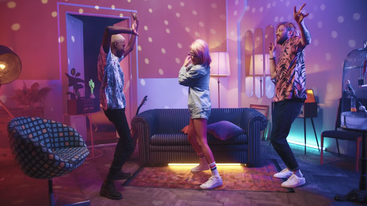 tres amigos hipster multiétnicos pasando un buen rato mientras bailan enérgicamente en una fiesta retro en casa