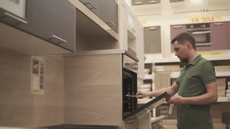 man checking out a kitchen oven in a showroom