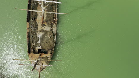 rusty red shipwreck stuck in shallow green water