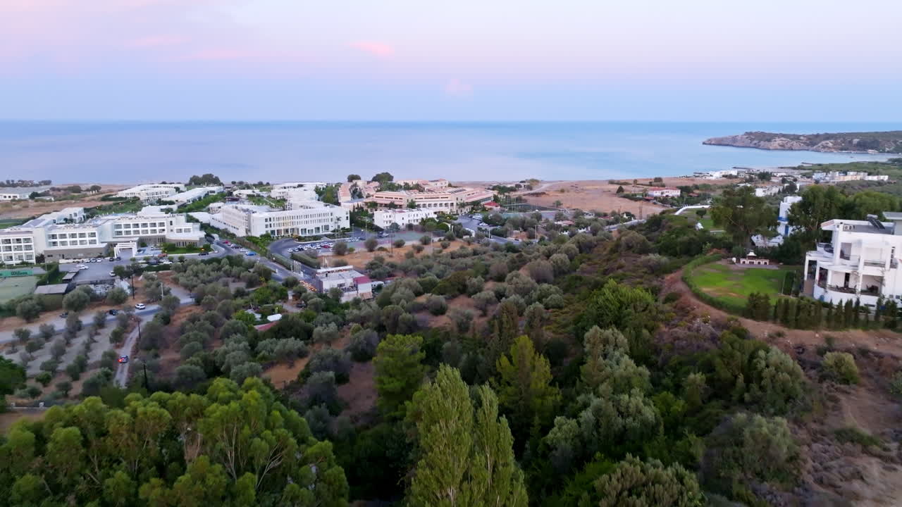 Aerial view over hilltop villas, toward resorts of coast of Rhodes, dusk in Greece
