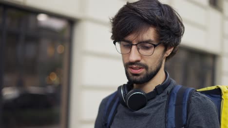 delivery man with backpack calling to a client on the street