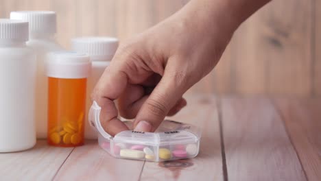 hand taking pills from a pill organizer with other bottles of medicine