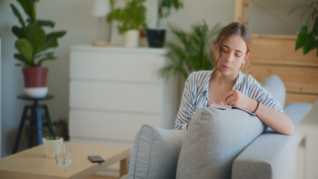 소파 에 메모 를 쓰고 있는 상적 인 여자