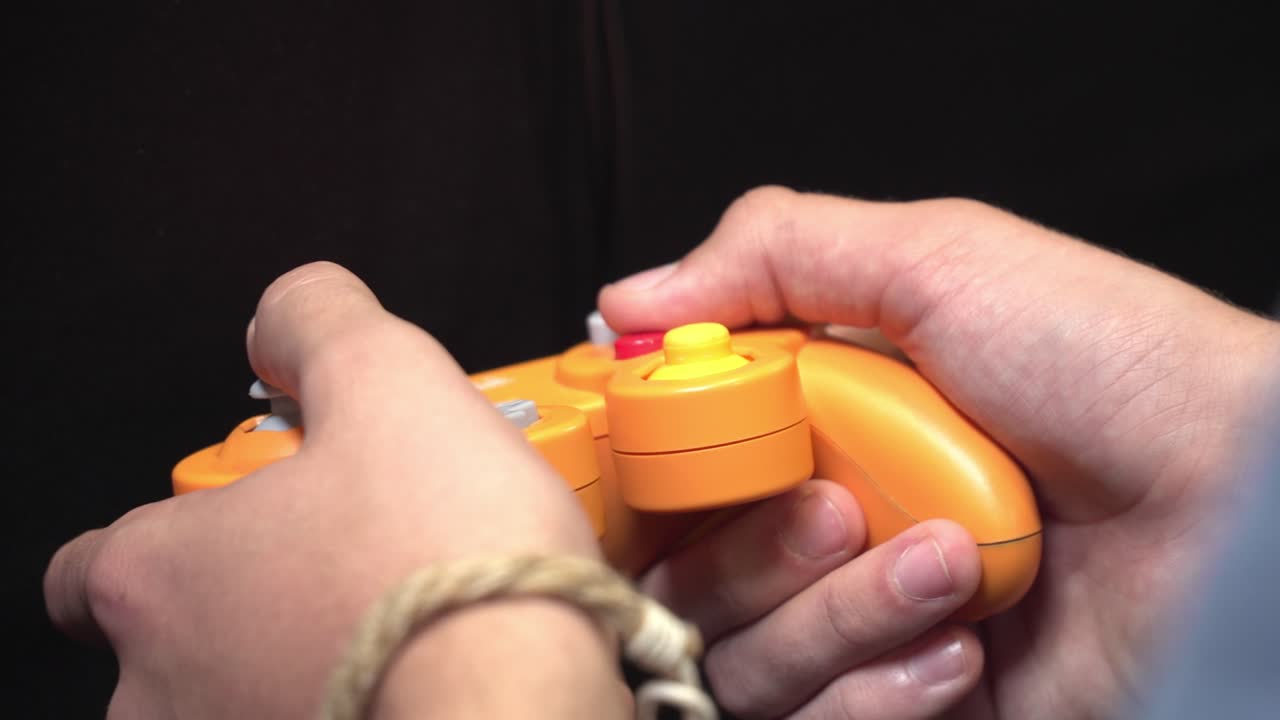 Primo piano di un giocatore che tiene un controller retrò mentre gioca a un videogioco in stile classico.