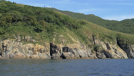 boat sails parallel to a rocky shore in primorye bay