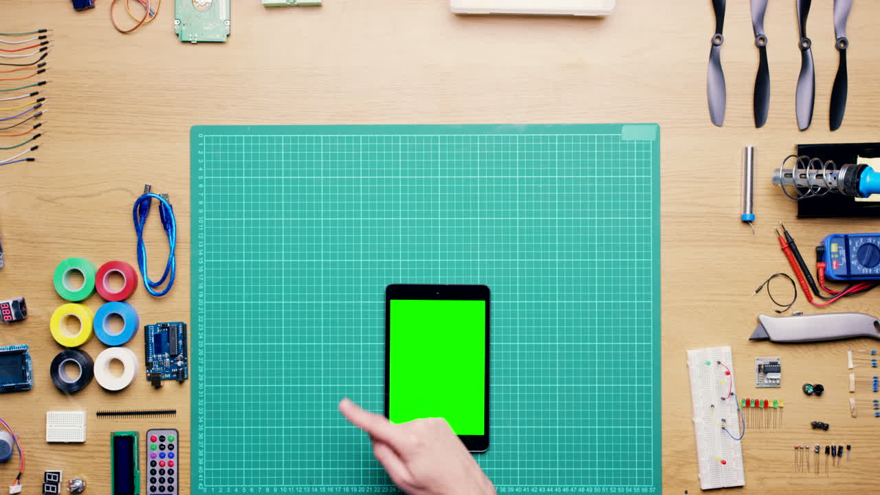 녹색 화면을 가진 태블릿을 사용하여 전자 프로젝트에서 일하는 사람