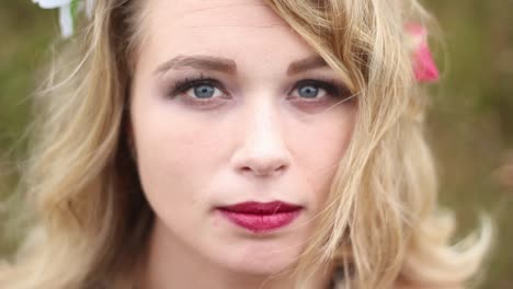 Attractive-young-woman-with-blue-eyes-looking-into-camera-in-a-windy-field