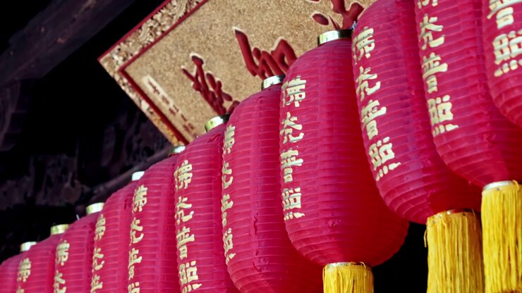 En række røde lanterner, prydet med guldbogstaver og gule kvaster, hænger fremtrædende i et tempel i Shanghai. Ideel til kulturelle dokumentarer eller rejseindslag.