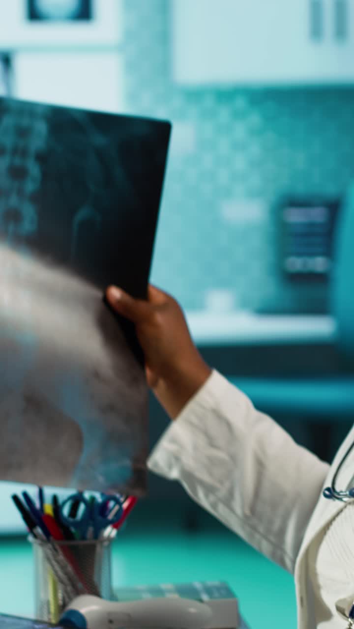 African American Doctor Examining X-Ray Film and Laptop in Medical Office