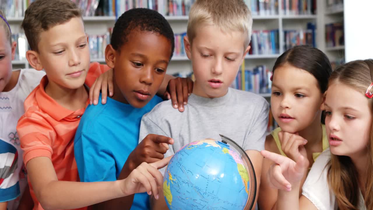 niños de la escuela mirando el globo en la biblioteca