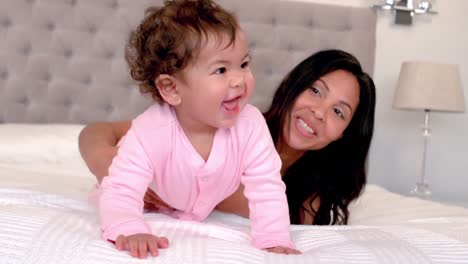 madre jugando con la hija bebé en la cama