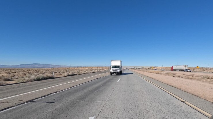 guida in autostrada attraverso il deserto del mojave passando davanti a un camion mentre guardi fuori dal lunotto