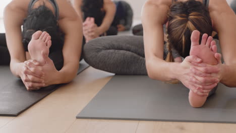 Clase-De-Yoga-Grupo-De-Mujeres-Jóvenes-Practican-La-Pose-De-Flexión-Hacia-Adelante-De-La-Cabeza-A-La-Rodilla-Disfrutando-De-Un-Estilo-De-Vida-Saludable-Haciendo-Ejercicio-En-La-Meditación-Del-Gimnasio