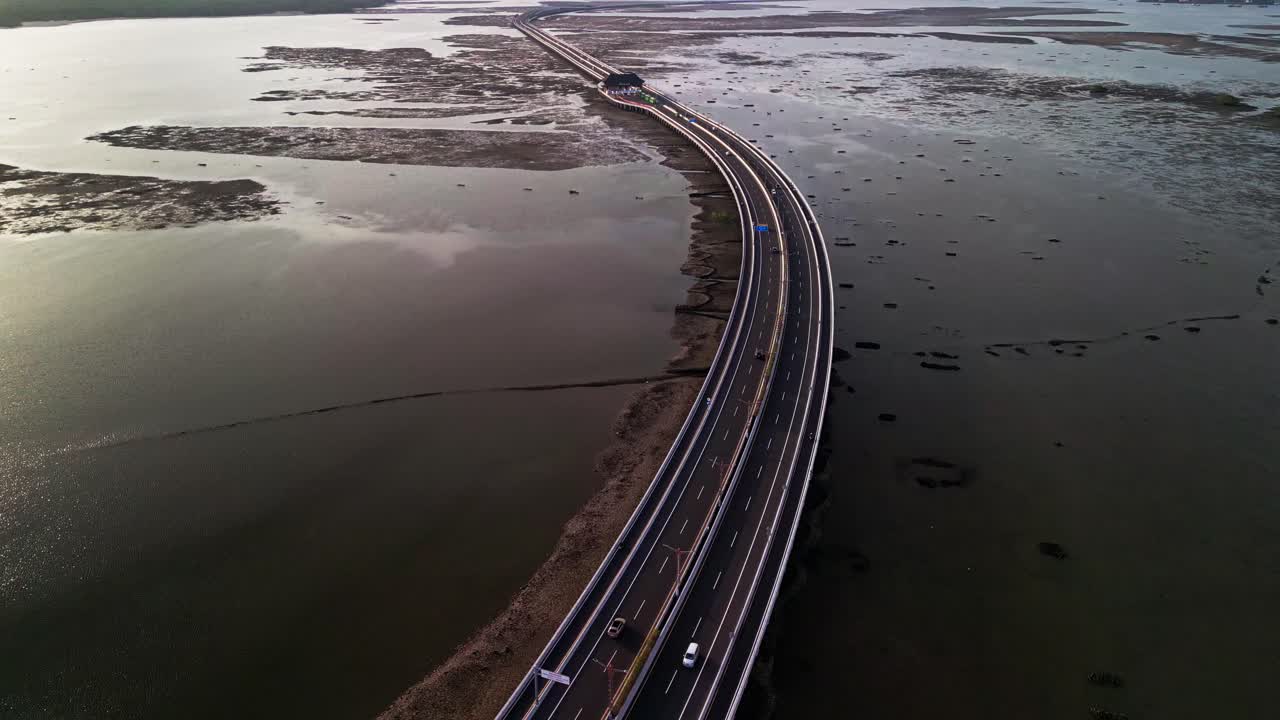 From above Bali Mandara Toll road curves across wide tidal mudflats revealed at low tide the drone footage highlights tropical coastal patterns and the strong design of the island bridge
