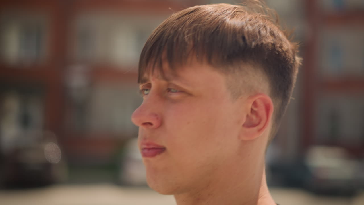 차량 근처에서 휴식을 취하는 십 대 스포츠 스타, 자동차 옆에서 휴식을 취하는 젊은 백인 운동선수, 주차된 차량 사이에서 편안하게 앉아 있는 백인 혈통의 십 대 스포츠 선수