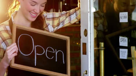 Waitress-showing-chalkboard-with-open-sign