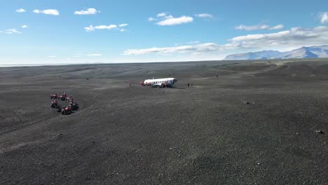 grupo de turistas en quads explorando el avión estrellado de islandia, vista aérea