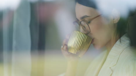 Vista-De-Una-Mujer-Tomando-Café-A-Través-De-La-Ventana-De-La-Oficina.