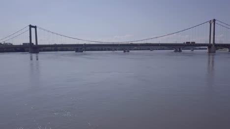 River-Rhone-transportation-bridge-crossing-low-angle-aerial-view-over-water-towards-suspension-connection