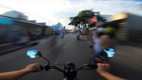 pov of commuter riding motor bike scooter on road in tropical beach town