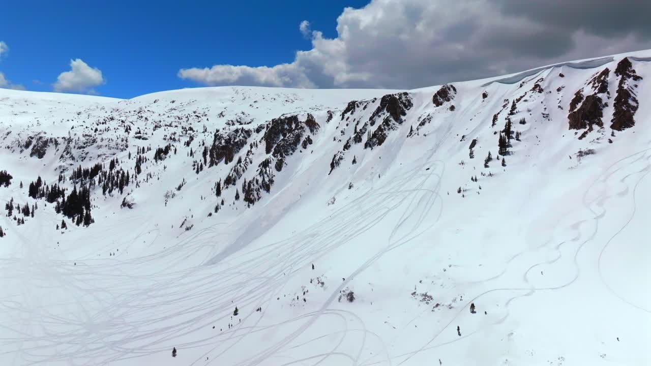Montezuma Deer Creek winter spring deep backcountry powder snow aerial drone Colorado snowmobile tracks avalanche terrain cornice chute Rocky Mountain peaks sunny blue skies clouds snowmobile forward