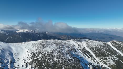 Drohnenschuss,-Rila-Gebirge,-Wolken-In-Der-Nähe,-Sonniger-Tag,-Blauer-Himmel,-Schneebedeckte-Gipfel-In-Der-Ferne,-Bulgarien