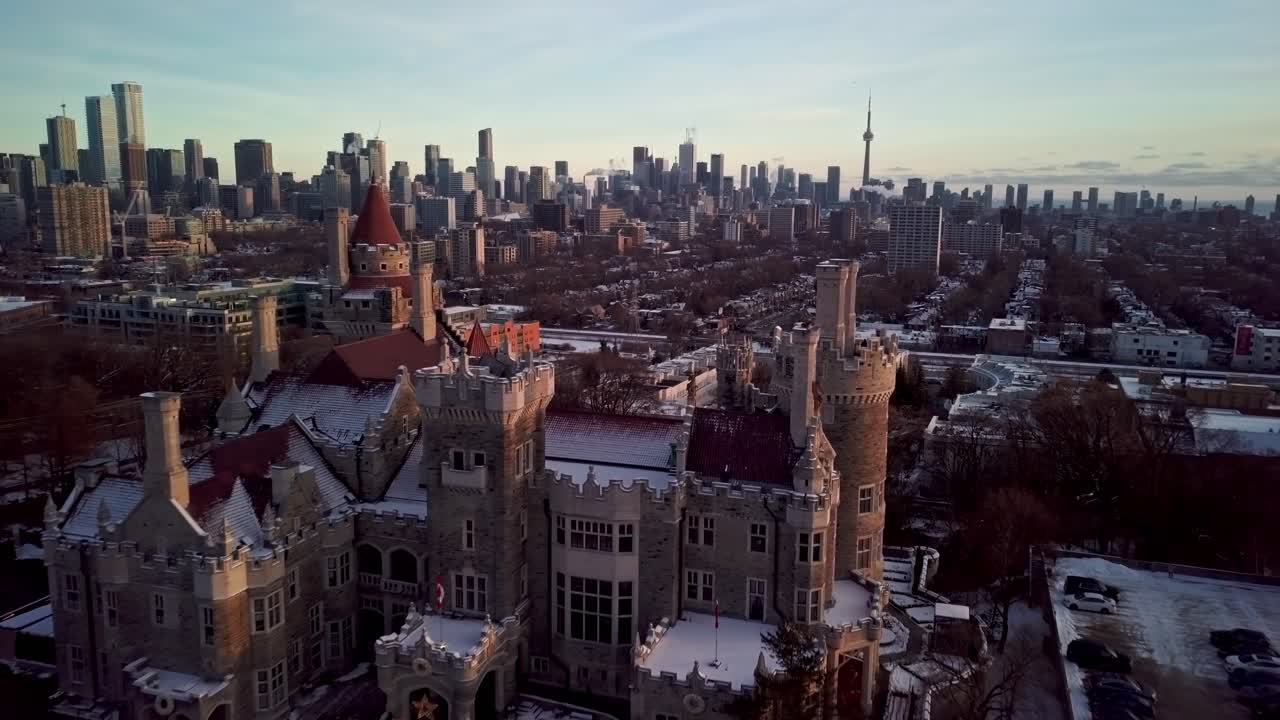 Contrasting Old and New Architecture in Snowy Big City, Drone Parallax. Flying over the Turrets and Red Tile Roof of a Castle with the Downtown Toronto Skyline behind in Winter Golden Hour