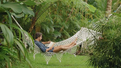 young man lying in hammock reading a book