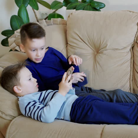 preschool boys holds modern mobile phone and plays cheerfully video game. focus on smartphone.