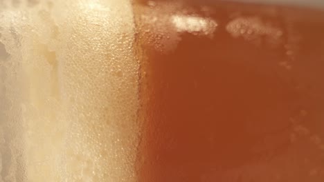 vertical footage of turntable platform of rotating cold beer pint in glass