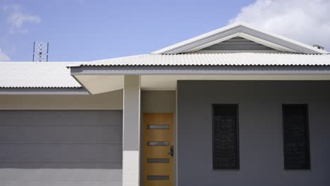 frente a una casa gris a nivel del suelo recién construida con césped verde y un garaje con puerta enrollable-1