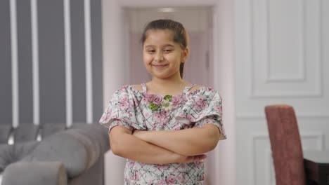 una niña india feliz y confiada de pie con las manos cruzadas