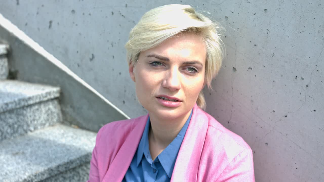 A businesswoman sitting on stair in a pensive with anxiety quiet break. A professional woman looking worried. a woman expressing a hangover attitude with her eye looking tired and sleepy