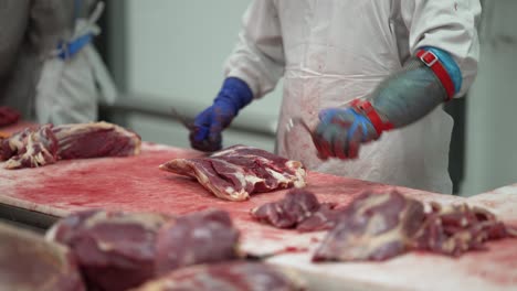 beef cuts being separated from fat by workers with a knife at a meat processing plant, close up shot