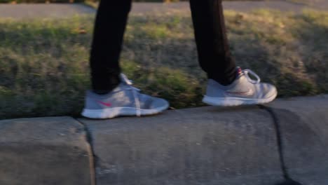 niña pequeña cuerda apretada caminando por la acera en un barrio jugando afuera al atardecer brazos extendidos cabello soplando en la brisa