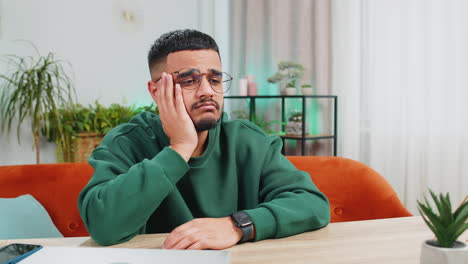 indian man at home suffers from unfair situation problem break up depressed feeling bad burnout