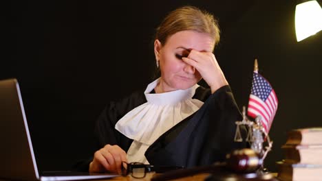 a focused female judge is intently engaged with her laptop, exhibiting various expressions while in the courtroom